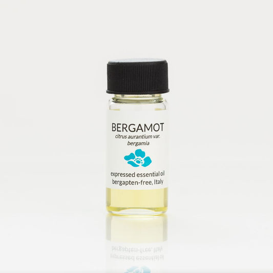 Bottle of bergamot essential oil with a black cap on a white background